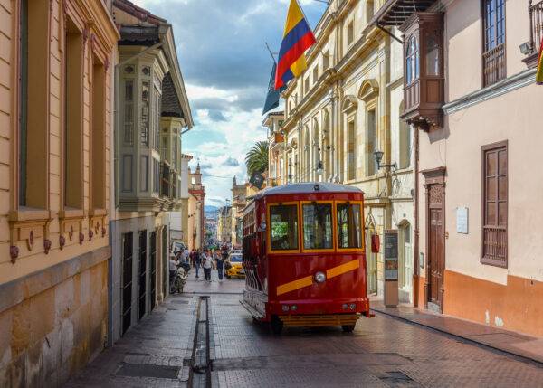 Historic La Candelaria neighborhood in Bogota, Colombia. This photo represents a typical street in the district and contains some people, vehicles, street art, and graffiti.